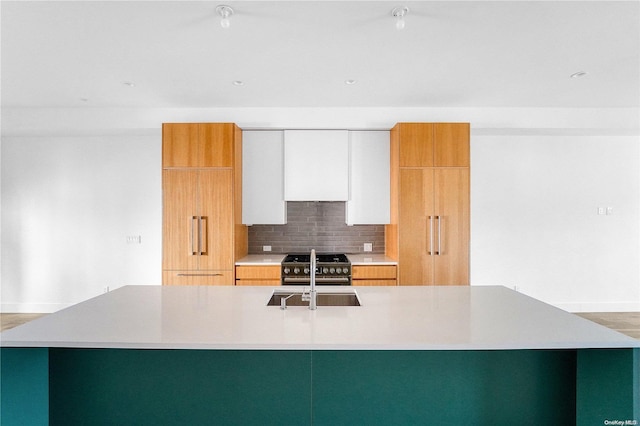 kitchen with decorative backsplash, a spacious island, white cabinetry, and sink