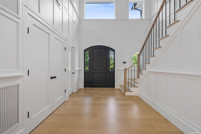 foyer featuring light hardwood / wood-style floors, a high ceiling, and a wealth of natural light