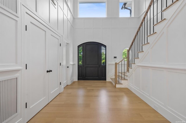 293 Beaver Dam Rd, Brookhaven, NY 11719 - entryway with a decorative wall, light wood finished floors, stairs, a high ceiling, and arched walkways
