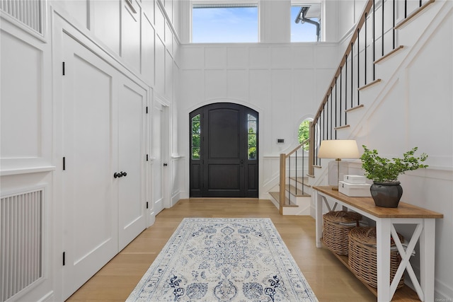 foyer featuring a towering ceiling and light hardwood / wood-style flooring