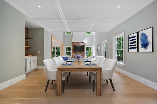 dining space featuring beam ceiling, crown molding, coffered ceiling, and light hardwood / wood-style floors