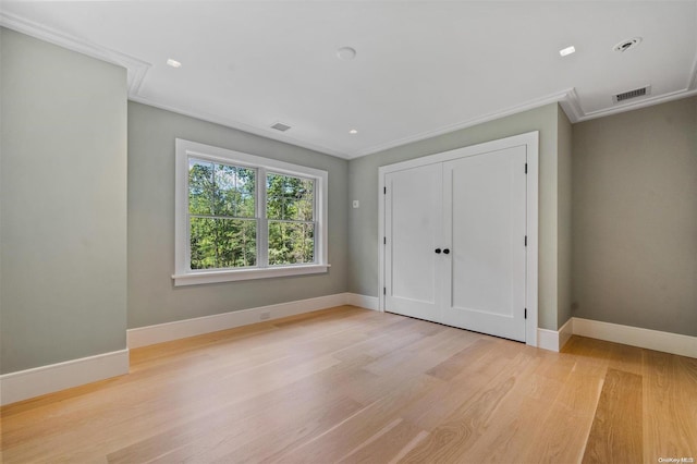 unfurnished bedroom with crown molding, a closet, and light hardwood / wood-style flooring