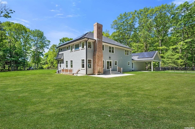 rear view of house with a lawn, a patio area, and solar panels