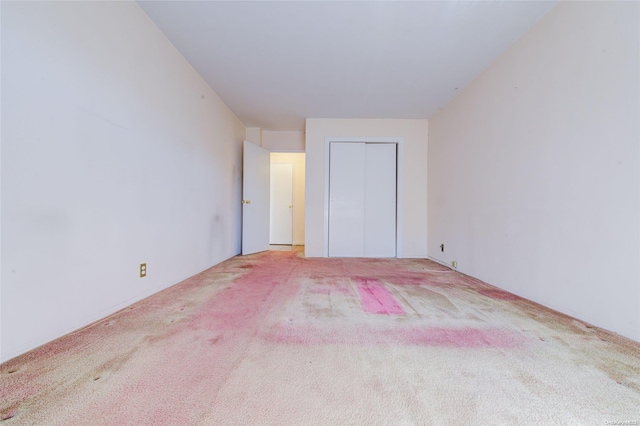 unfurnished bedroom featuring light colored carpet and a closet