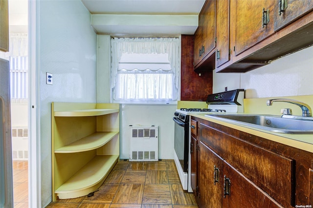 kitchen featuring white stove, radiator, and sink