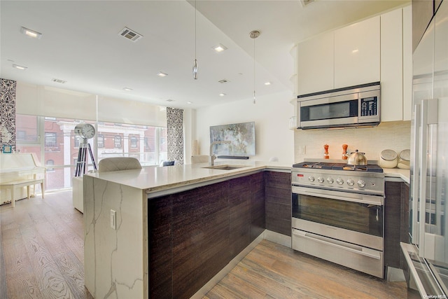 kitchen featuring sink, decorative backsplash, light hardwood / wood-style floors, white cabinetry, and stainless steel appliances