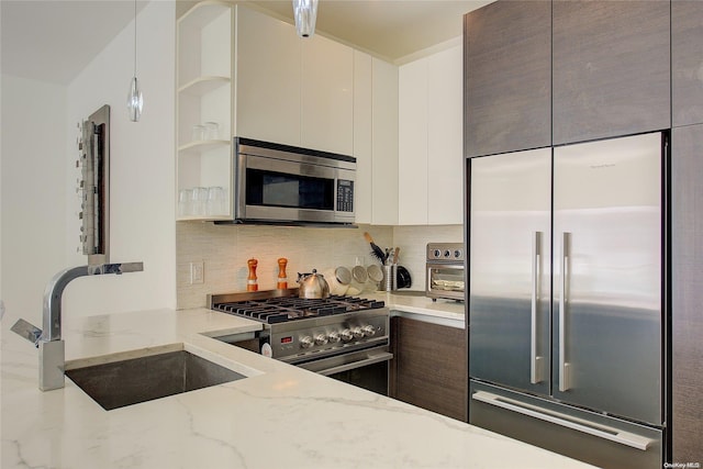 kitchen featuring light stone countertops, sink, backsplash, white cabinets, and appliances with stainless steel finishes