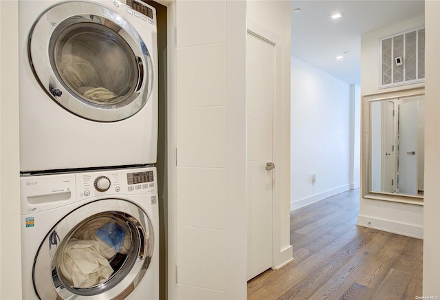 laundry area featuring hardwood / wood-style floors and stacked washer / dryer