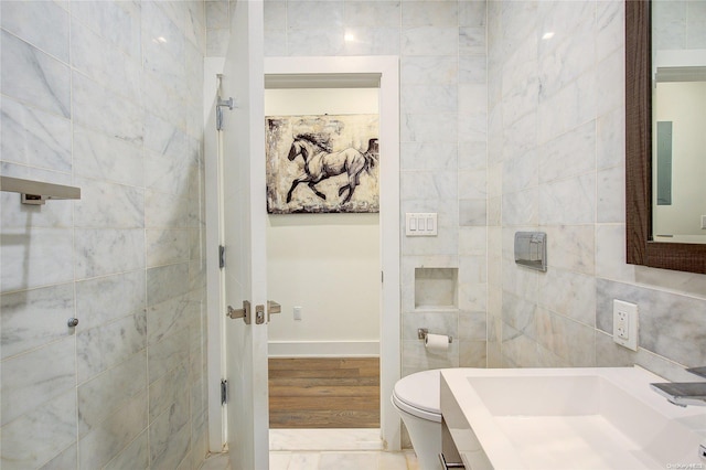 bathroom with sink, tile walls, and toilet