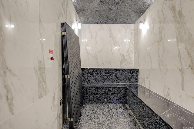 bathroom with tiled shower and tile walls