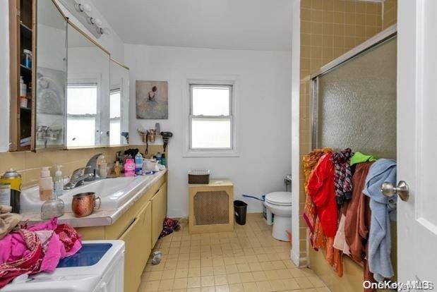 bathroom with vanity, toilet, and a shower with door