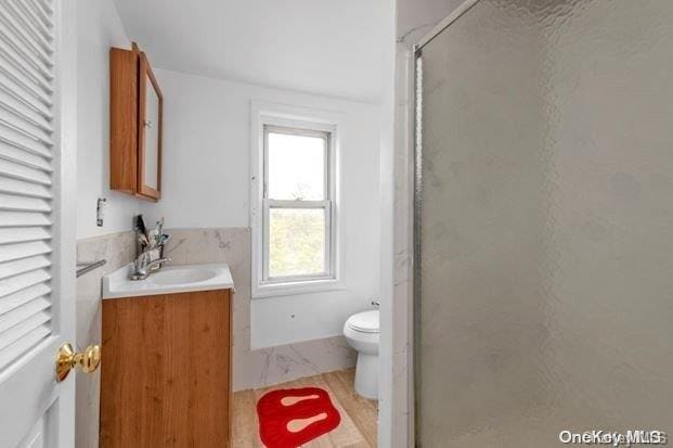 bathroom featuring vanity, toilet, and a shower with shower door