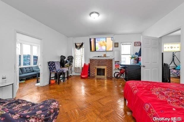 bedroom featuring parquet flooring and a brick fireplace