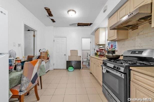 kitchen featuring light tile patterned floors, backsplash, stainless steel range with gas cooktop, and sink