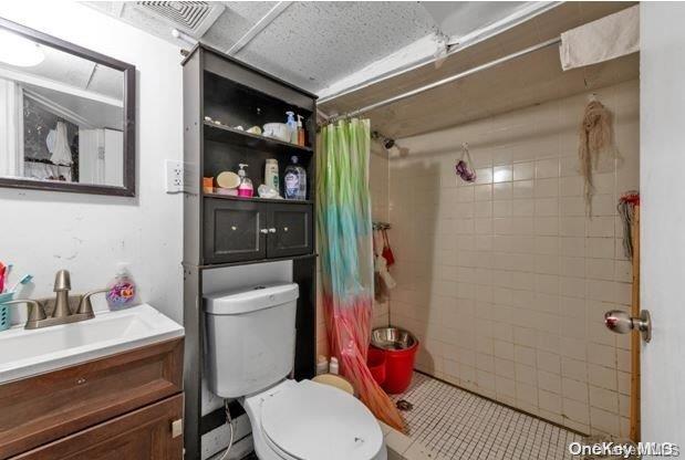 bathroom featuring tile patterned flooring, toilet, vanity, and a shower with shower curtain