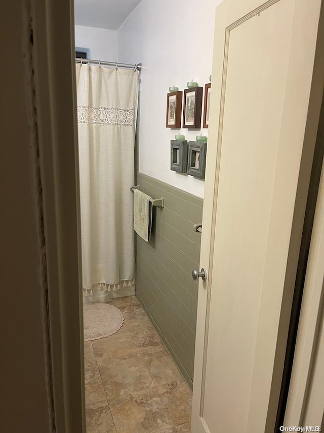 bathroom with tile walls and a shower with shower curtain