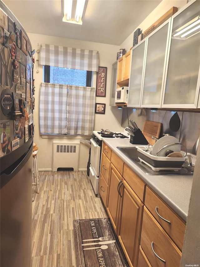 kitchen featuring radiator, light hardwood / wood-style flooring, and white appliances