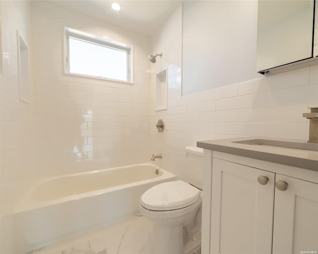 full bathroom with tile walls, vanity, tiled shower / bath combo, and toilet