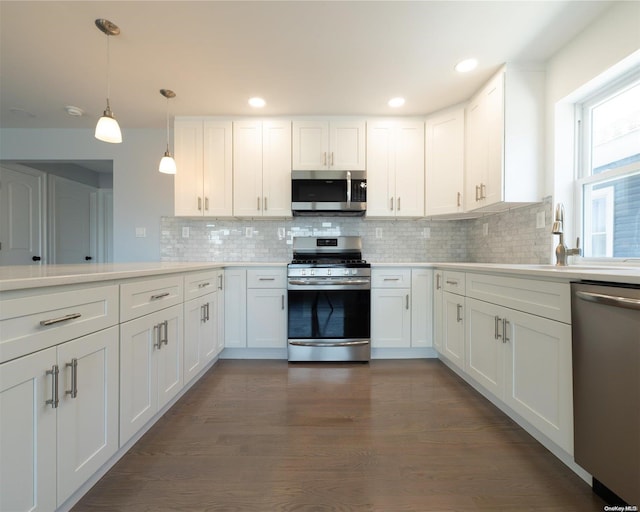 kitchen with decorative backsplash, dark hardwood / wood-style flooring, stainless steel appliances, decorative light fixtures, and white cabinets