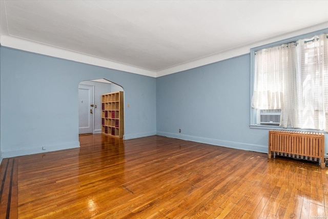 empty room with radiator, crown molding, and hardwood / wood-style floors