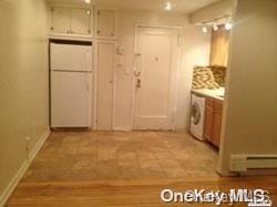 interior space with white fridge, a baseboard radiator, and washer / clothes dryer