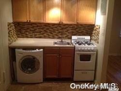 kitchen with washer / dryer, white range with gas cooktop, and sink