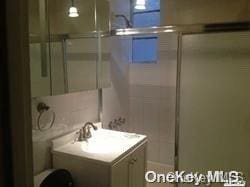 bathroom with a shower with shower door and sink