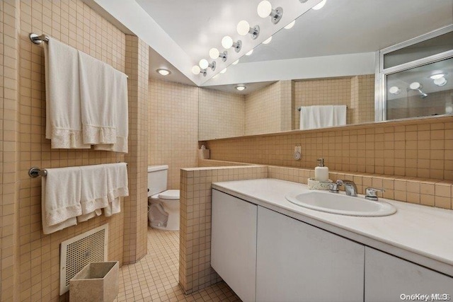 bathroom with tile patterned flooring, toilet, decorative backsplash, vanity, and tile walls