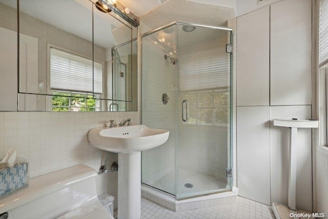 bathroom with tile patterned flooring, a shower with shower door, and tile walls