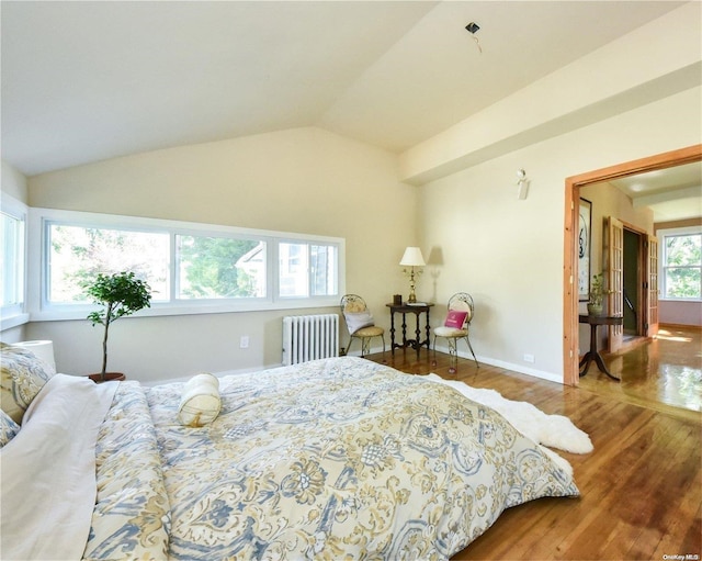 bedroom featuring hardwood / wood-style flooring, radiator, and lofted ceiling