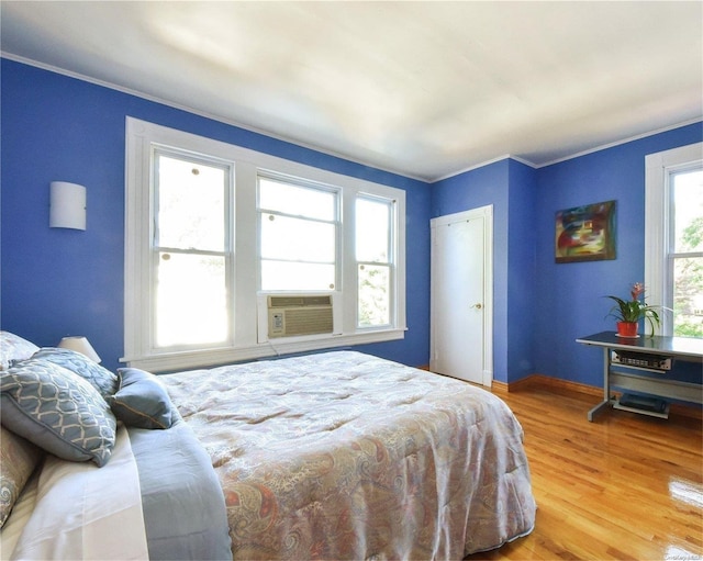 bedroom with hardwood / wood-style flooring, cooling unit, and crown molding