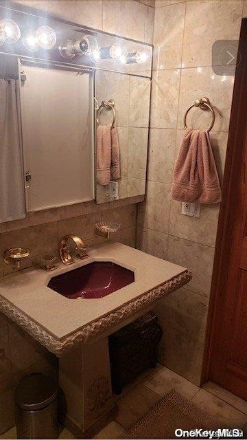 bathroom with tile patterned floors, sink, and tile walls