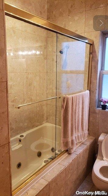 bathroom with toilet and tiled shower / bath