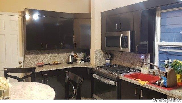 kitchen with decorative backsplash, black electric range, dark brown cabinets, and sink