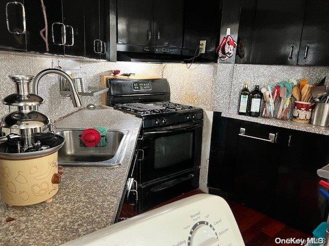 kitchen with exhaust hood, black gas stove, sink, decorative backsplash, and light stone countertops