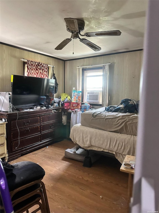 bedroom with hardwood / wood-style flooring, ceiling fan, cooling unit, and wood walls