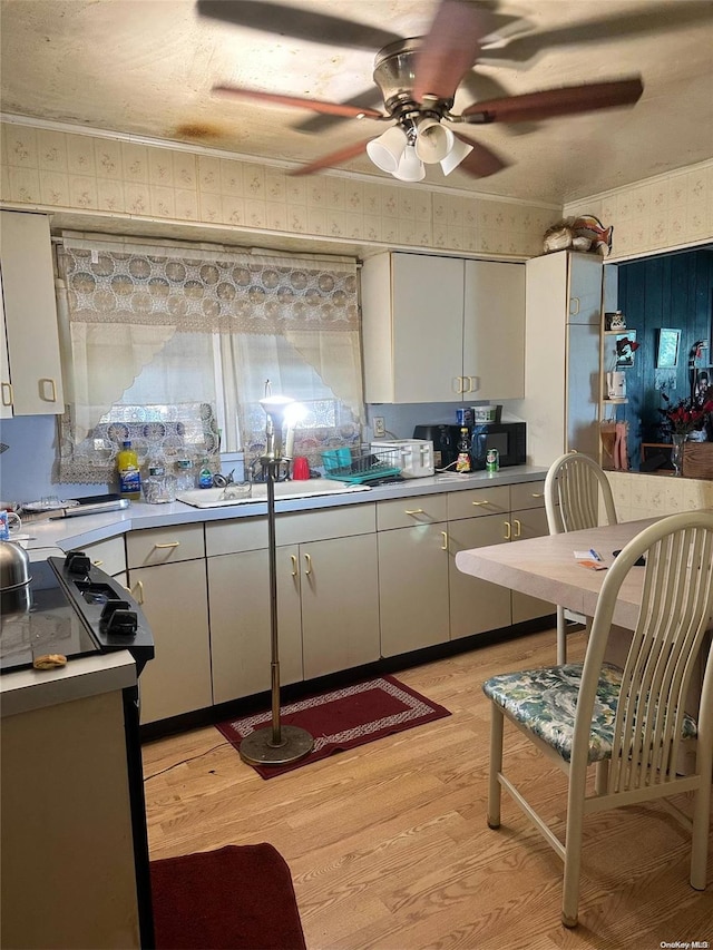 kitchen with light hardwood / wood-style flooring, white cabinets, stove, and sink