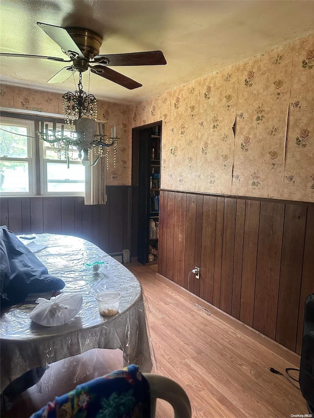 bedroom featuring hardwood / wood-style floors, ceiling fan, and wooden walls