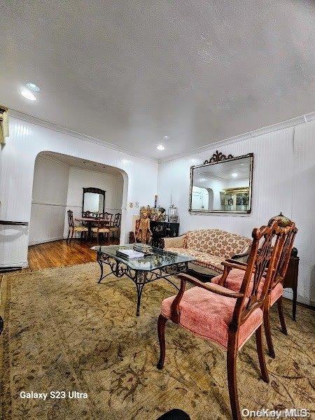 living room with crown molding, a textured ceiling, and hardwood / wood-style flooring