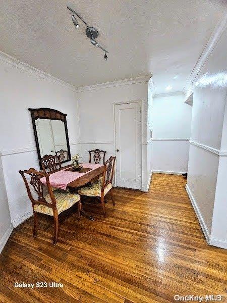 dining room featuring wood-type flooring, track lighting, and ornamental molding