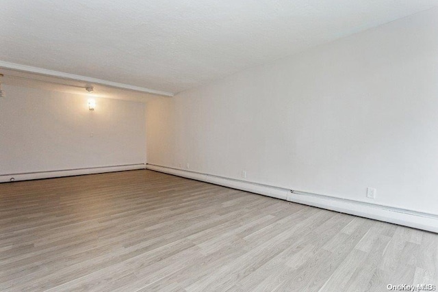 empty room featuring light hardwood / wood-style floors, a textured ceiling, and a baseboard heating unit