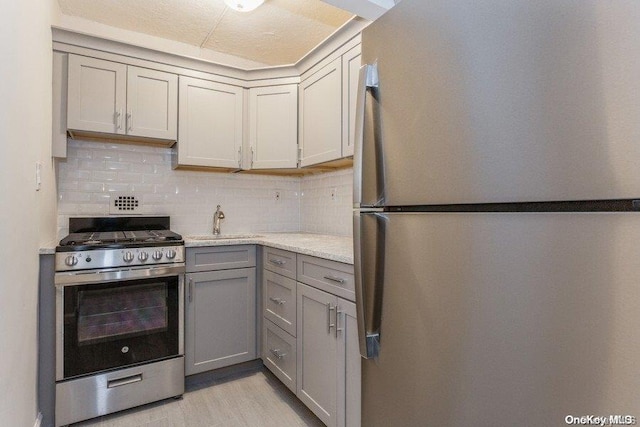 kitchen featuring tasteful backsplash, gray cabinetry, sink, and appliances with stainless steel finishes