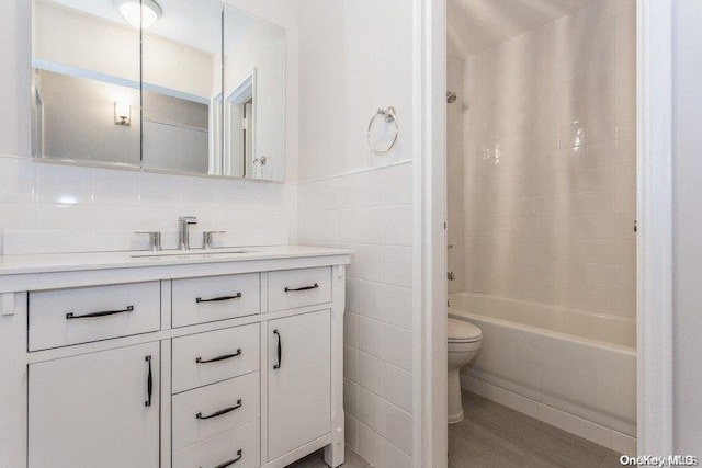 full bathroom with hardwood / wood-style floors, vanity, bathing tub / shower combination, and tile walls