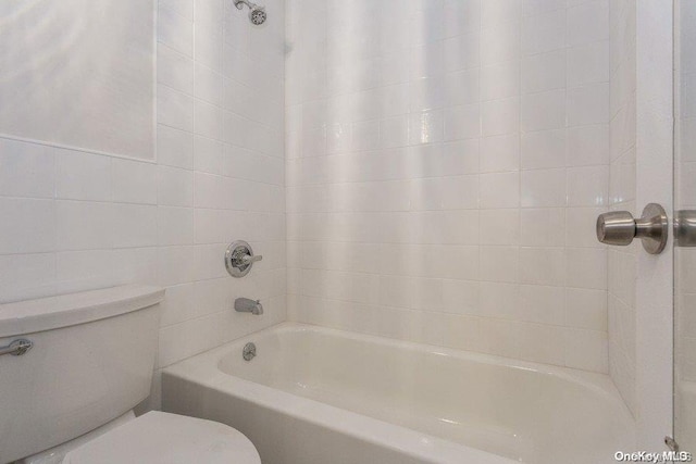 bathroom featuring toilet and tiled shower / bath