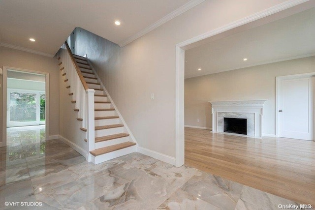 stairway featuring wood-type flooring, ornamental molding, and a premium fireplace