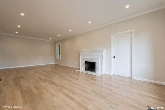 unfurnished living room with a premium fireplace, ornamental molding, and light hardwood / wood-style flooring