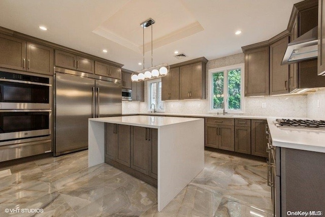 kitchen with a center island, hanging light fixtures, appliances with stainless steel finishes, and tasteful backsplash