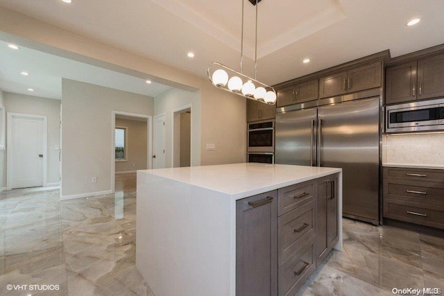 kitchen with tasteful backsplash, dark brown cabinetry, pendant lighting, built in appliances, and a center island