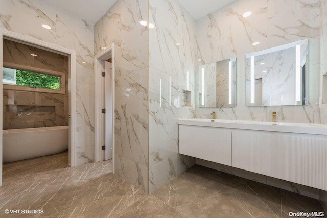 bathroom with vanity, a tub to relax in, and tile walls