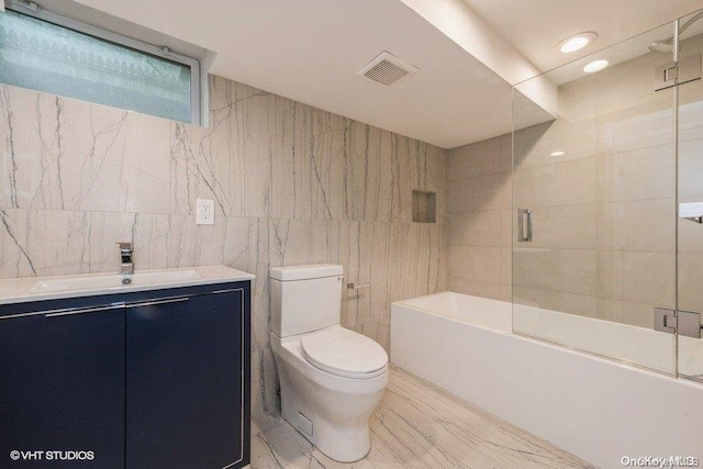 full bathroom featuring vanity, toilet, enclosed tub / shower combo, and tile walls